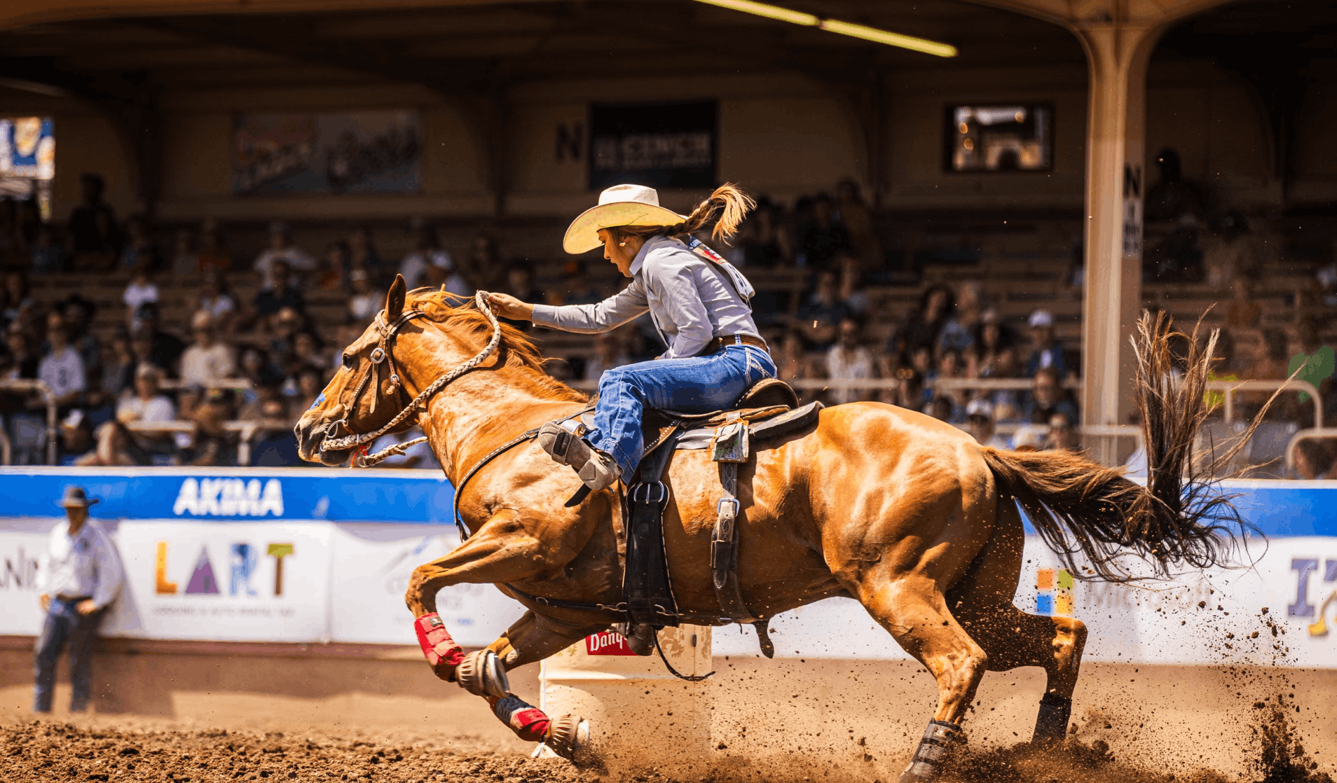Barrel racer turning hard around a barrel in front of a full grandstand